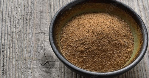 Dry mango powder in a small bowl. Rustic wooden table with space for text.