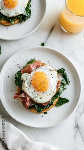 Enjoy a delightful breakfast featuring English crumpets layered with savory prosciutto, fresh spinach, and perfectly cooked eggs paired with refreshing orange juice