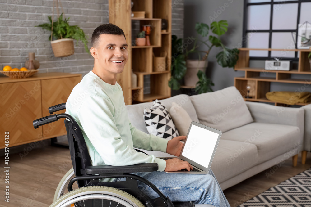 Happy young man in wheelchair using laptop at home Happy young man in wheelchair using laptop at home