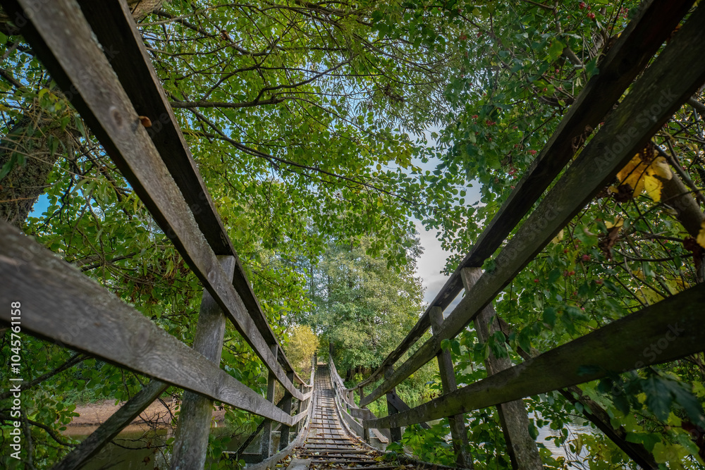 Old, wooden, pedestrian bridge on the background of the autumn river