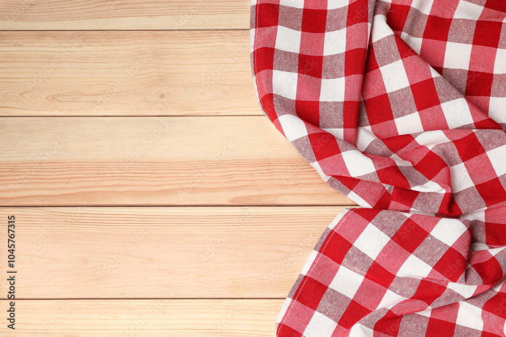 Obraz premium Crumpled tablecloth with checkered pattern on light wooden table, top view. Space for text