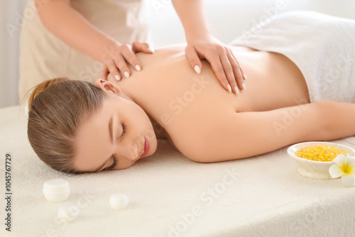 Young woman undergoing massage procedure in spa salon