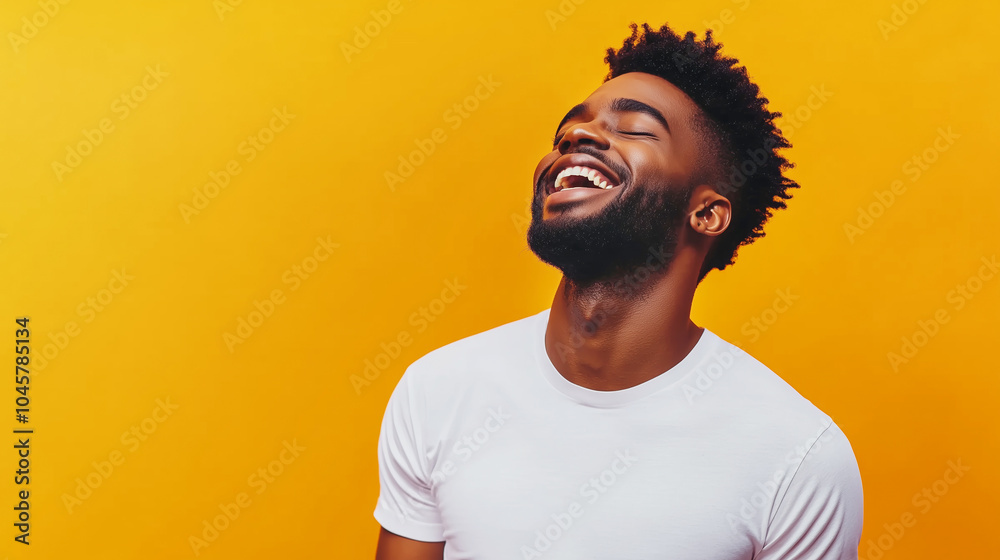 Joyful man in white t-shirt laughing against vibrant yellow background