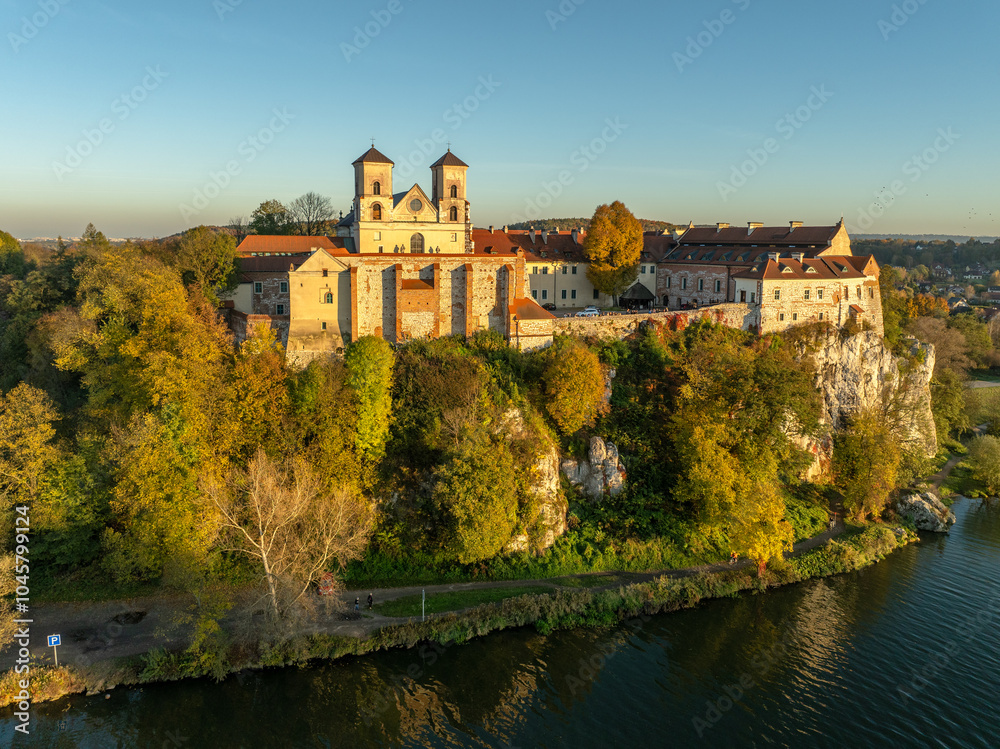 Tyniec near Krakow, Poland. Active Benedictine abbey, monastery and church on the rocky cliff and Vistula River in autumn in sunset light with trees in fall colors