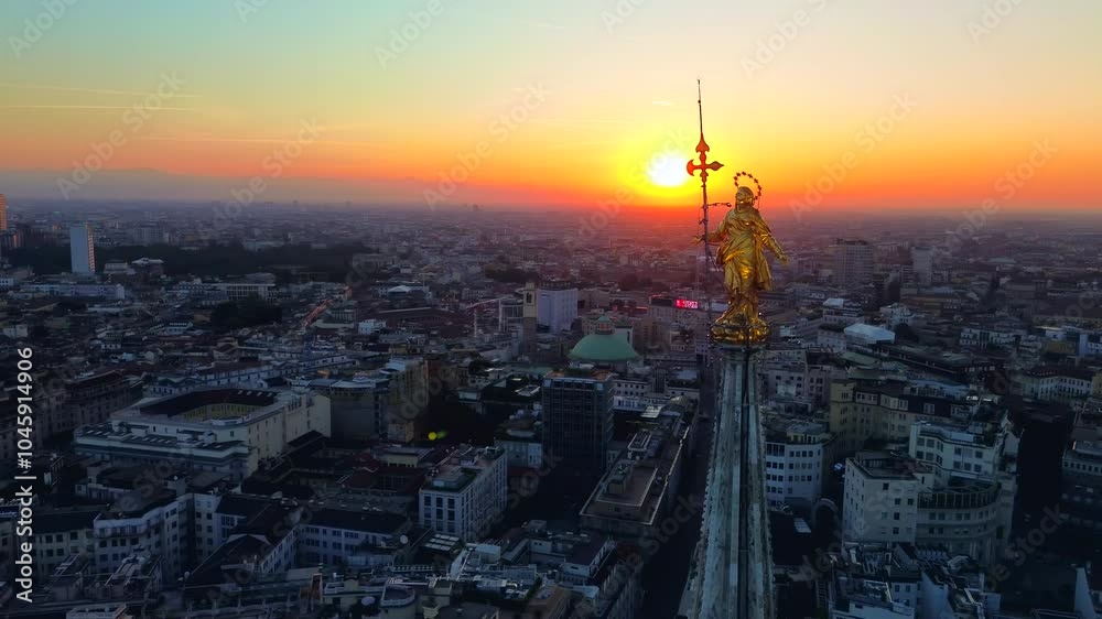 Aerial view of the statue of the Madonna on the central spire of the Duomo and the city's cathedral at dawn. Roofs of houses and skyscrapers. Sun over the horizon. duomo square. Italy Milan 19.09.2024 Aerial view of the statue of the Madonna on the central spire of the Duomo and the city's cathedral at dawn. Roofs of houses and skyscrapers. Sun over the horizon. duomo square. Italy Milan 19.09.2024