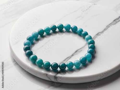 aqua blue jade bracelet neatly arranged on a smooth white marble surface.