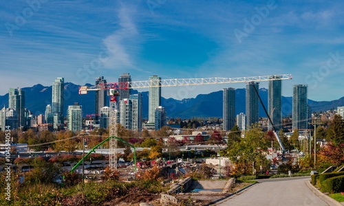 A new construction site in downtown Burnaby, opposite a residential area with a mountain range in the background
