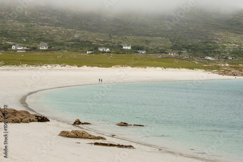 White sandy beach and ocean with blue turquoise color water. Dog bay, county Galway, Ireland. Popular tourist area with stunning Irish nature scenery. Cloudy sky. Travel and tourism. photo