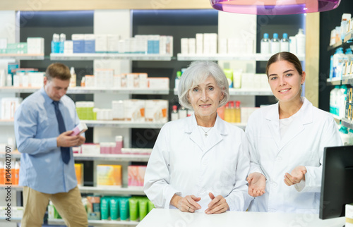 Senior woman and girl pharmacists are standing in pharmacys sales hall, pharmacy staff are amicably preparing to meet chemist shop visitors photo