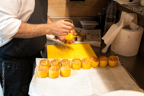 Chef skillfully seasoning pastries in a bustling kitchen photo