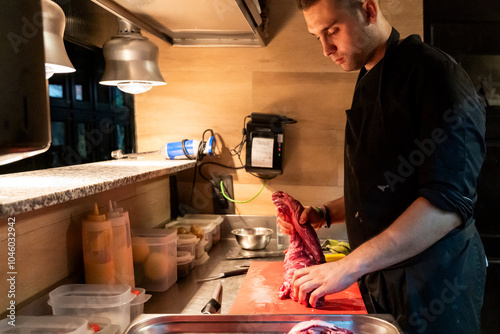 Chef preparing meat in a professional kitchen photo