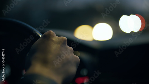 The driver's hand on the steering wheel against the background of the night road