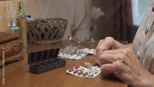 Old woman putting pills into pill box medicine container. Hands close-up.