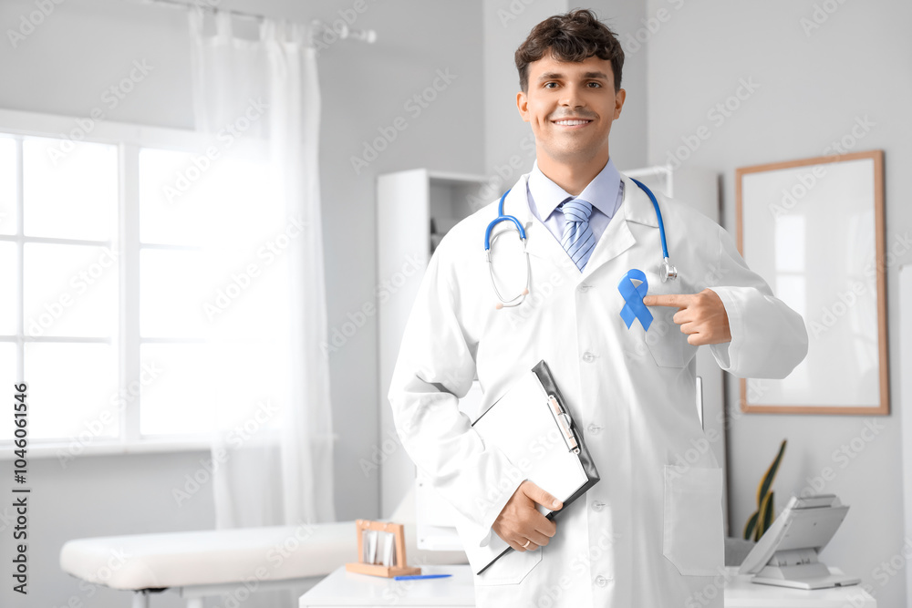 Fototapeta premium Male doctor with blue ribbon and clipboard in clinic. Prostate cancer awareness concept