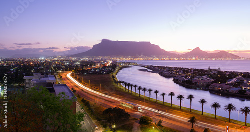 Table Mountain and illuminated Cape Town city, with the lagoon reflecting sunset hues and Woodbridge Island photo