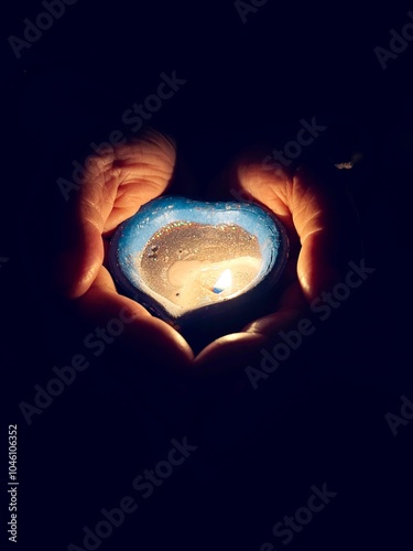 hand holding a blue burning candle on black background. photo