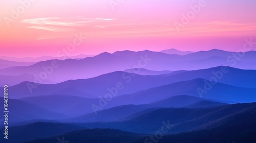 Silhouettes of mountains at sunset with a hazy pink and purple sky.