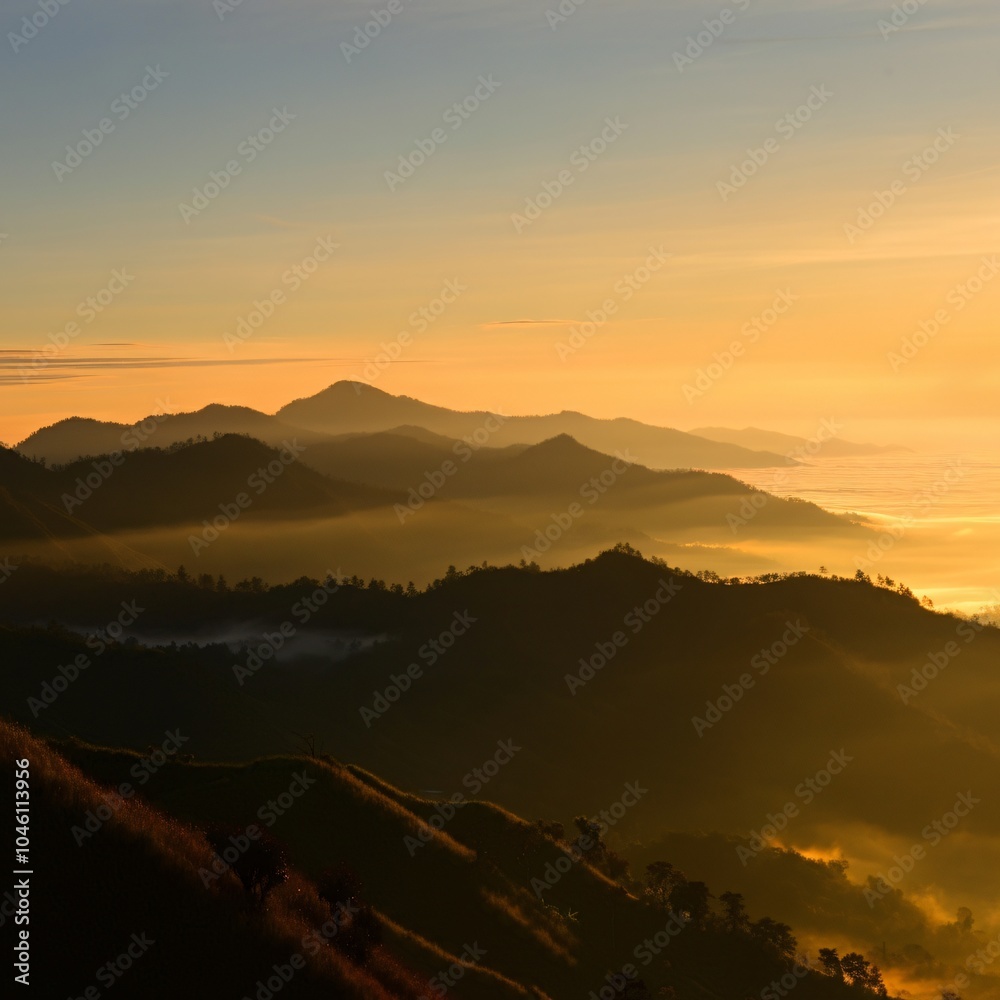 Naklejka premium Serene sunrise over a misty mountain range