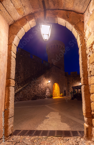 View of the tower of the castle of Tossa de Mar at night from under the arch, Spain photo