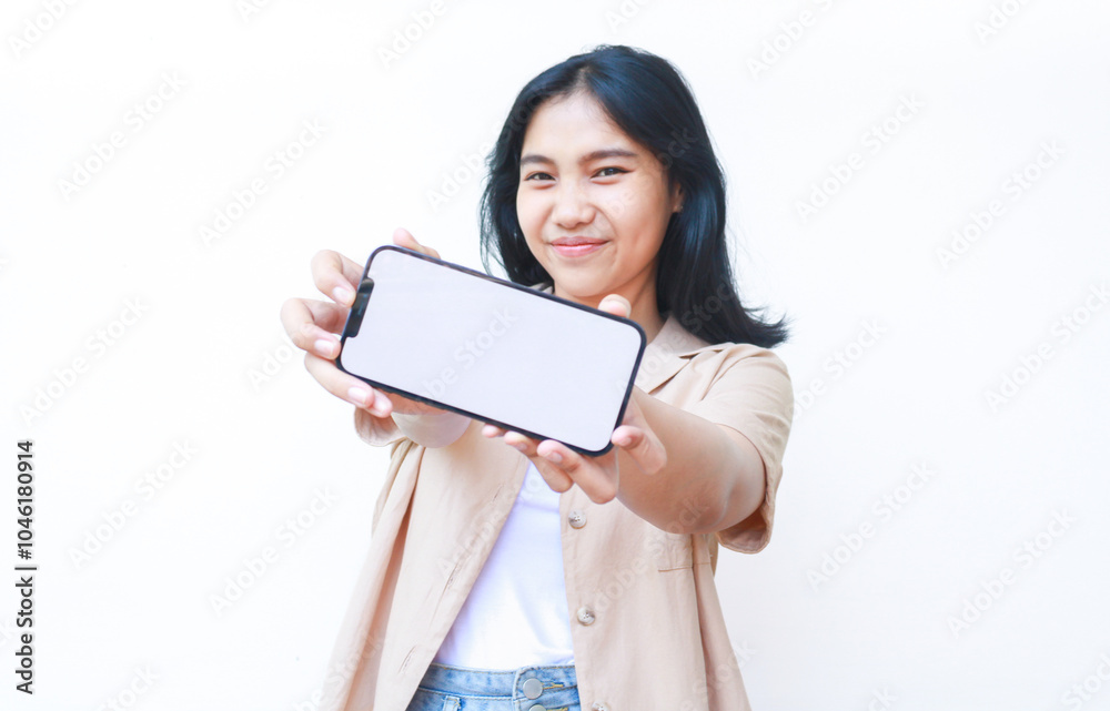 excited asian woman showing smartphone blank screen hold on hands to camera wearing casual brown clothes and jeans isolated on white background excited asian woman showing smartphone blank screen hold on hands to camera wearing casual brown clothes and jeans isolated on white background
