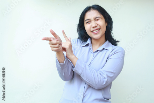 image of smiling beautiful young business woman manager pointing finger and blink eye excited to introduce product, wear formal shirt, isolated over white background