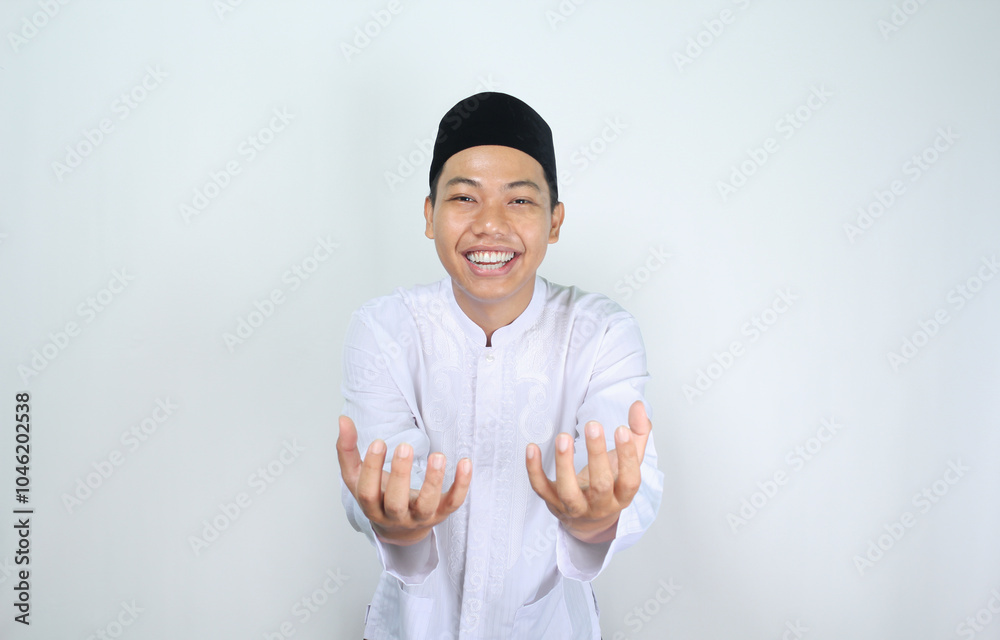 smiling asian muslim man showing empty palm at camera holding imaginary food plate isolated on white background smiling asian muslim man showing empty palm at camera holding imaginary food plate isolated on white background