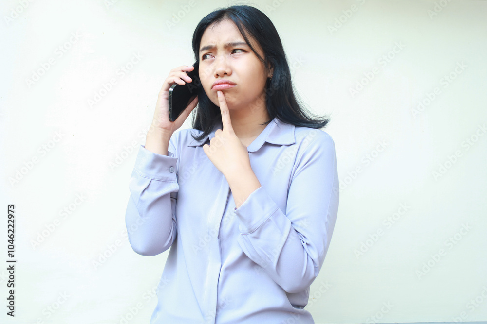 anxious worried asian young woman talking on mobile phone and thouch her chin with forefinger, female dressed in formal suit looking away, isolated over white background anxious worried asian young woman talking on mobile phone and thouch her chin with forefinger, female dressed in formal suit looking away, isolated over white background