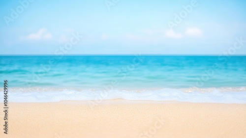 Beautiful blurred background of a sandy beach with blue sea water under the bright sun, perfect for summer vacation and travel themes. 