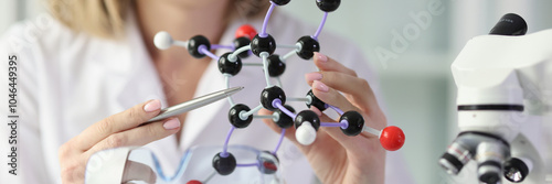 Obraz na płótnie Woman in white lab coat demonstrates model of molecule w salonie