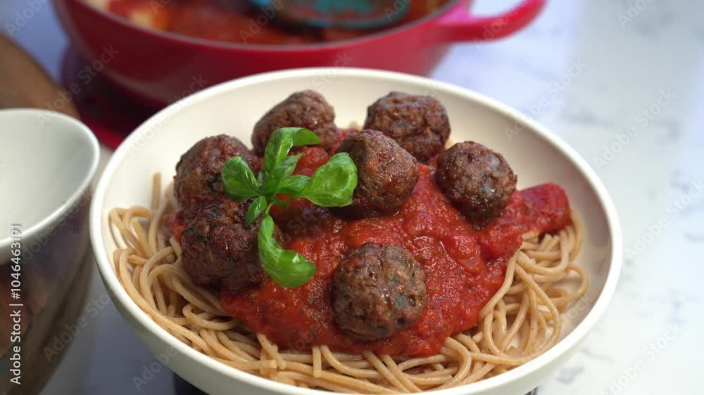 Meatballs and spaghetti with tomato sauce topped with fresh basil in a white bowl Meatballs and spaghetti with tomato sauce topped with fresh basil in a white bowl