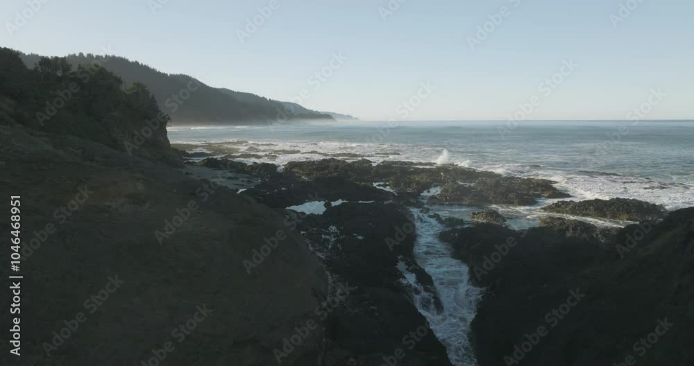 Aerial dolly between the rugged coastline at Cape Perpetua, Oregon Coast, with waves crashing into the rocky shore Aerial dolly between the rugged coastline at Cape Perpetua, Oregon Coast, with waves crashing into the rocky shore