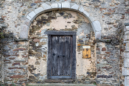 Hermitage of the Holy Christ. Stone facade and wooden entrance door. Lake Omaña, León, Spain.