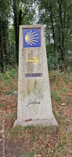Millestone with yellow scallop shell and arrow indicating way to Santiago de Compostela 