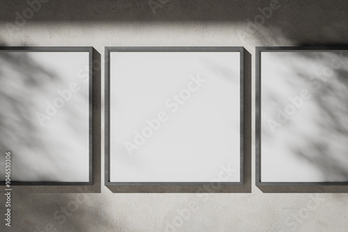 Three white blank square posters in a metal frame on a plaster wall photo