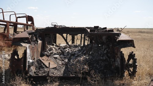 Burned and destroyed car in field. Concept of destruction due to war. photo