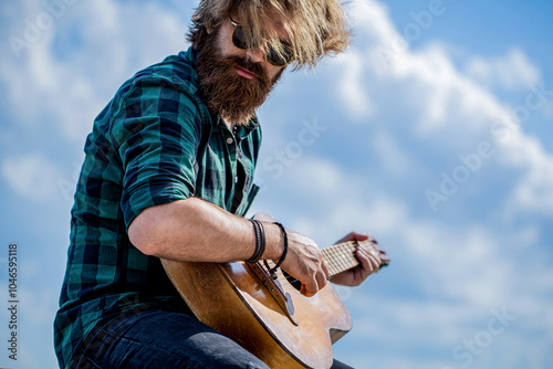 Guitar acoustic. Man plays the guitar, nature, sky background. Male musician playing guitar, music instrument. Man's hands playing acoustic guitar photo