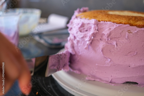 Pink cake being decorated with frosting