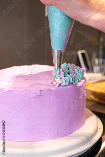 Pink cake being decorated with frosting