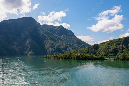 Scenic ferry boat tour on Lake Koman reservoir on Drin river surrounded by forested steep hills, cliffs and majestic rugged mountain ranges of Albanian Alps. Panoramic view along Albanian Fjords. Awe photo