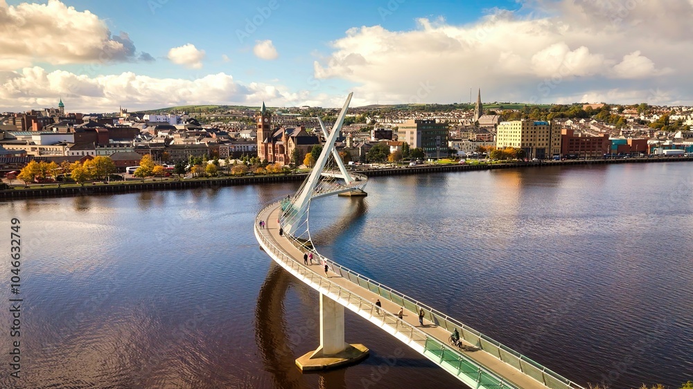 Fototapeta premium City of Derry aka Londonderry in Northern Ireland aerial view - A Dramatic Cityscape by the River Foyle Featuring a Beautiful Pedestrian Bridge