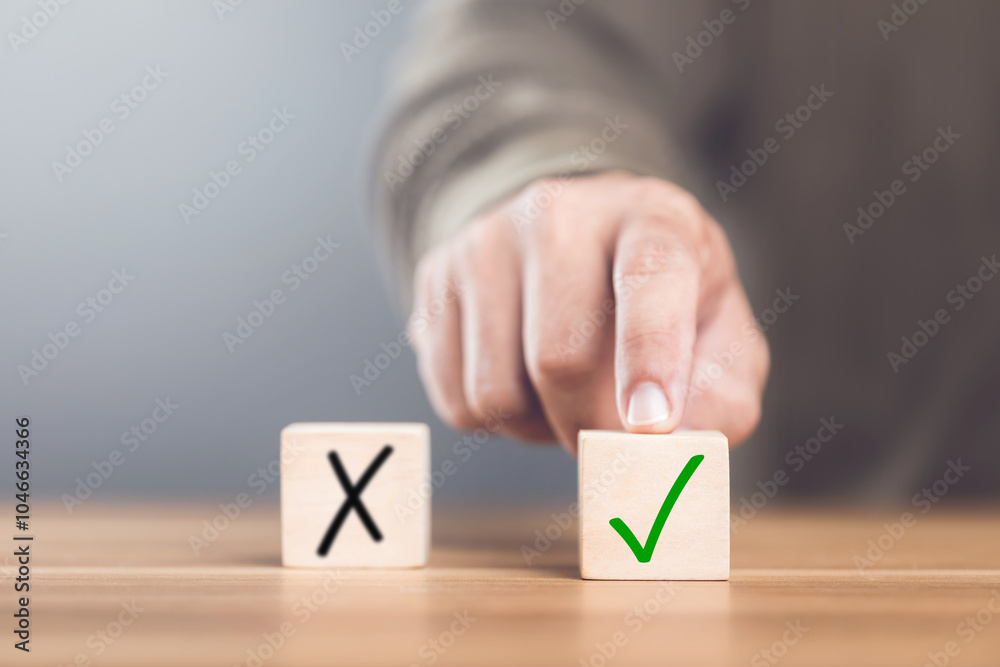 © SKT Studio - A man choosing between a checkmark and an 'X' symbol on wooden blocks. Image represents the concept of making the right choice, highlighting the importance of distinguishing between right and wrong © SKT Studio - A man choosing between a checkmark and an 'X' symbol on wooden blocks. Image represents the concept of making the right choice, highlighting the importance of distinguishing between right and wrong