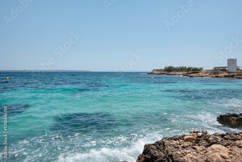Coastal views of the charming Playa de Illetes tucked away from tourists and surrounded by the blue Mediterranean Sea with rugged shoreline and gentle waves, Palma de Mallorca, Balearic Island, Spain