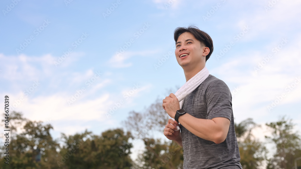 Smiling young sporty man jogging on a path surrounded by nature Smiling young sporty man jogging on a path surrounded by nature