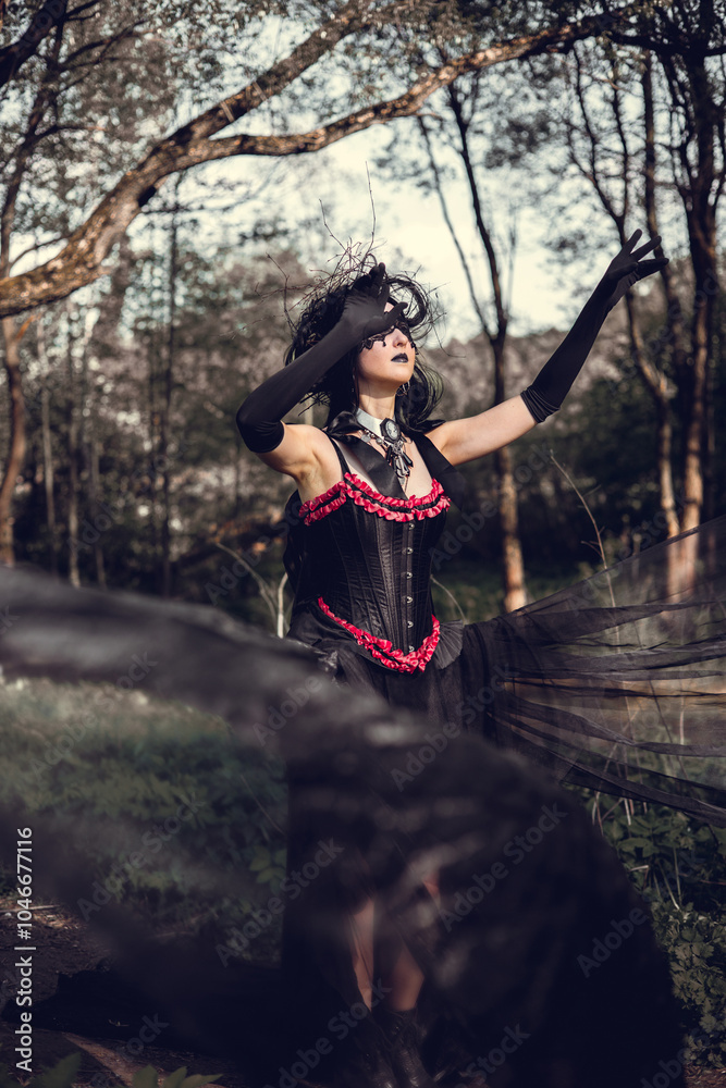 A young woman in the image of a witch and sorceress, standing in a dark forest, wearing a black dress with a train and a socket on her head. A young woman in the image of a witch and sorceress, standing in a dark forest, wearing a black dress with a train and a socket on her head.