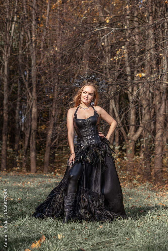 A young woman in the form of a witch and sorceress, standing in a dark forest, wearing a black dress with feathers. A beautiful gothic queen works wonders in the autumn forest on Halloween. A young woman in the form of a witch and sorceress, standing in a dark forest, wearing a black dress with feathers. A beautiful gothic queen works wonders in the autumn forest on Halloween.