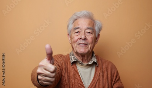 Elderly Man with Cheerful Expression Giving Thumbs Up Against Orange Background photo