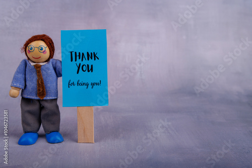 Whimsical wooden toy figure holding a bright blue banner with an inspiring message, encouraging positivity and motivation in daily lif photo