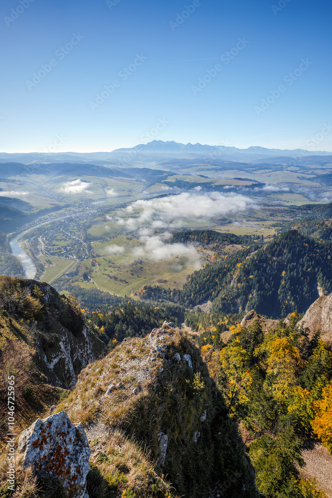 Beautiful mountain landscape. View from the Trzy Korony peak. The Tatra Mountains in the distance. The Dunajec River Valley. Autumn landscape. Clouds below the peaks. A winding river. Sromowce Niżne,