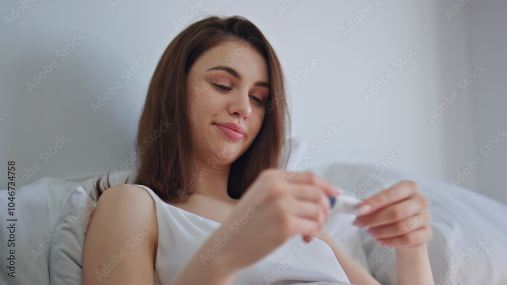 Concerned woman checking temperature in bedroom closeup. Young brunette in bed Concerned woman checking temperature in bedroom closeup. Young brunette in bed