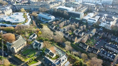 Aerial footage of Edinburgh, Scotland, featuring a wide cityscape with a clear view of Arthur’s Seat in the background. The shot captures a mix of modern buildings, and tree-lined streets.
